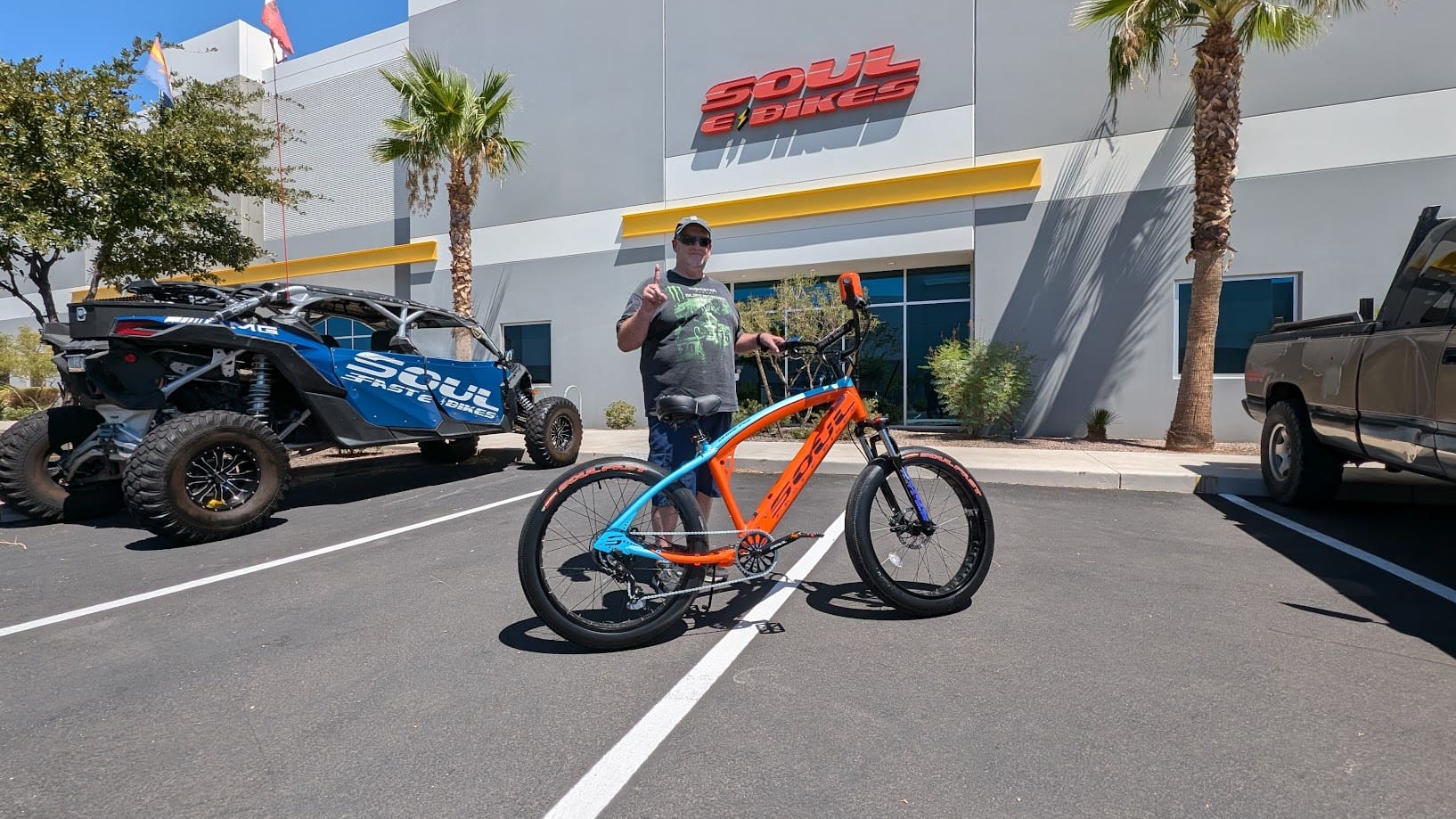 Person posing with colorful bicycle outside store.