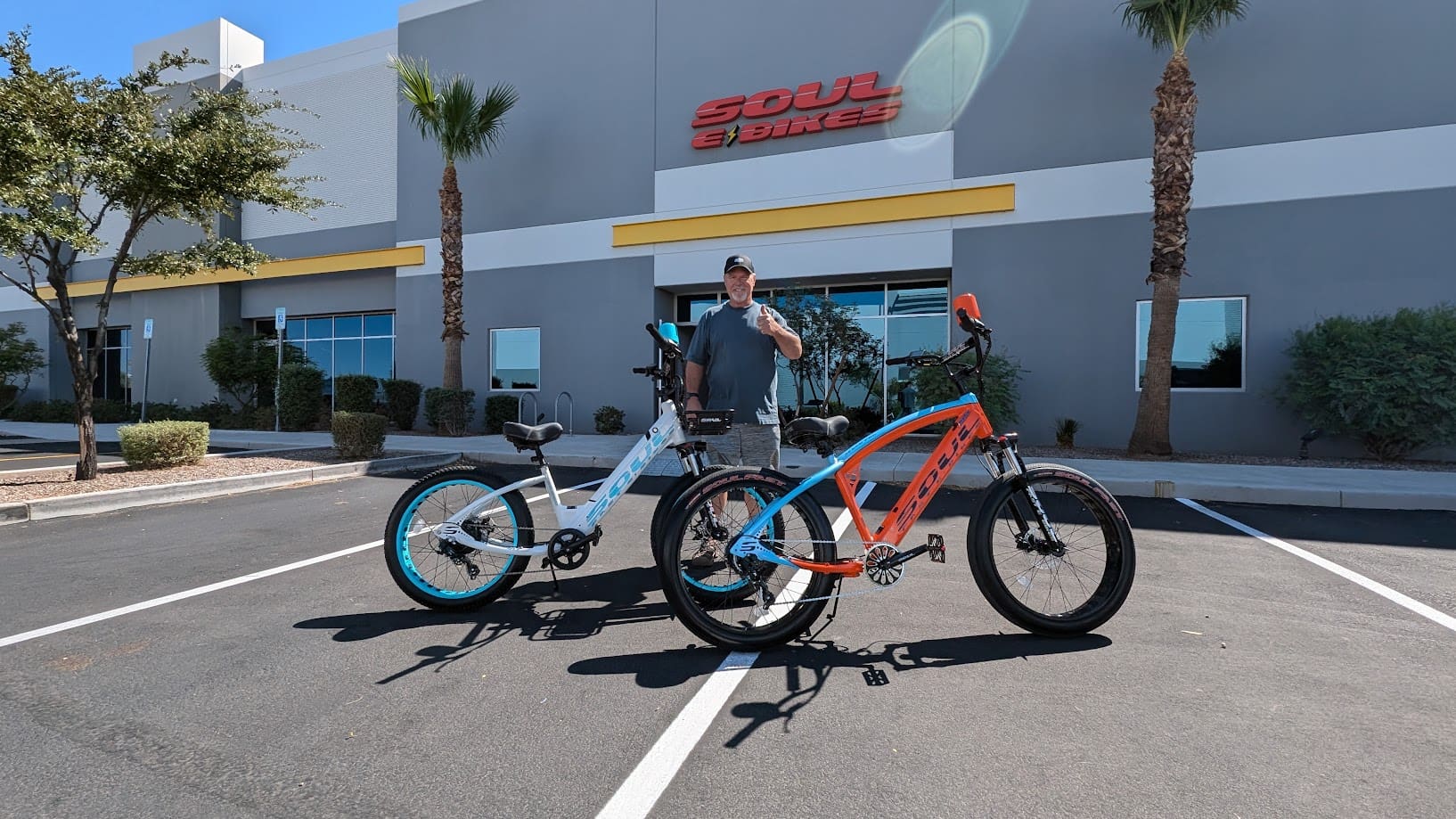 Man with two electric bikes outside building.