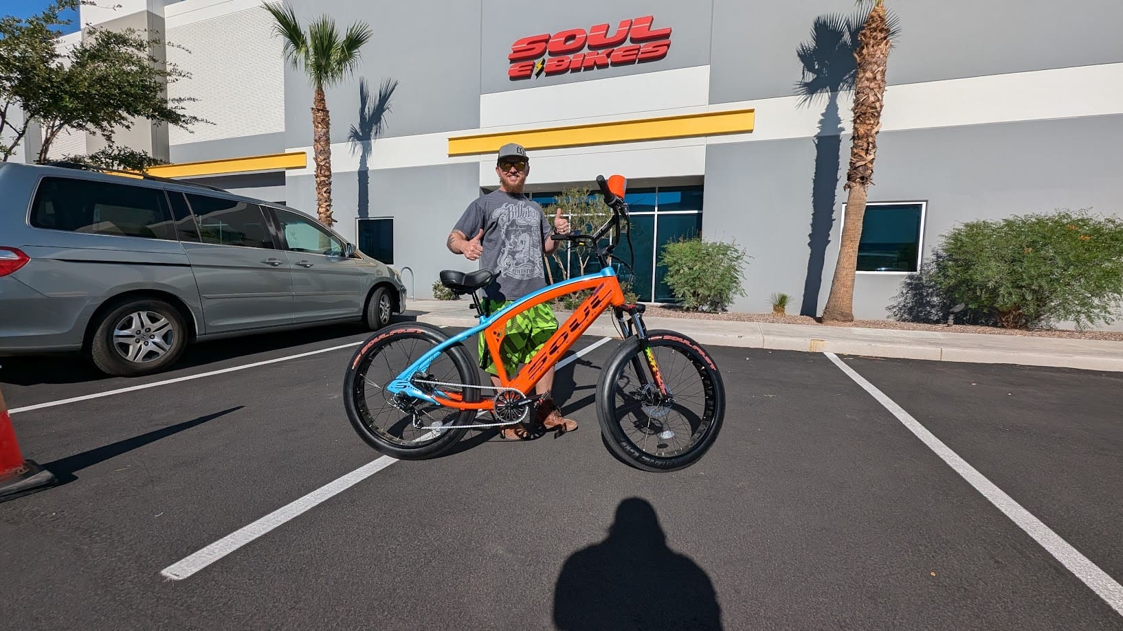 Person posing with colorful bicycle outside store.