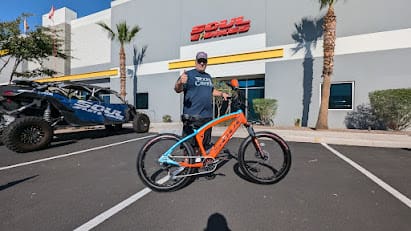 Man with orange bike in front of building.
