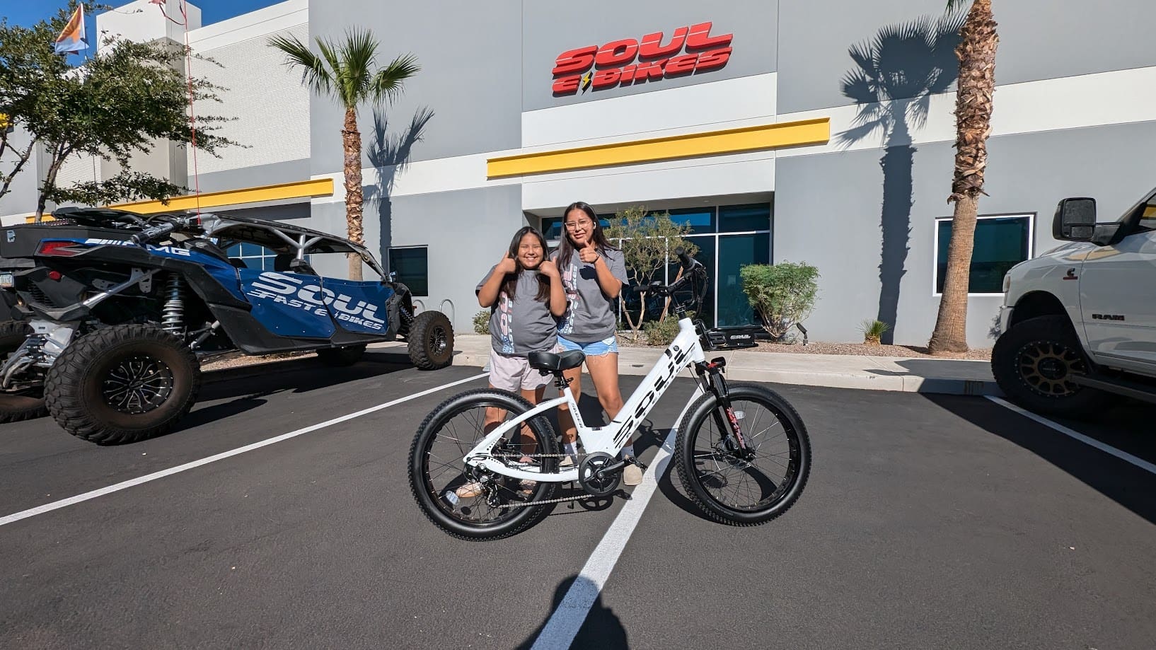 Two people posing with a bicycle outside.