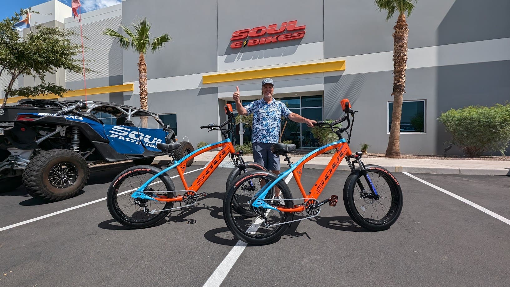 Man with electric bikes outside store.