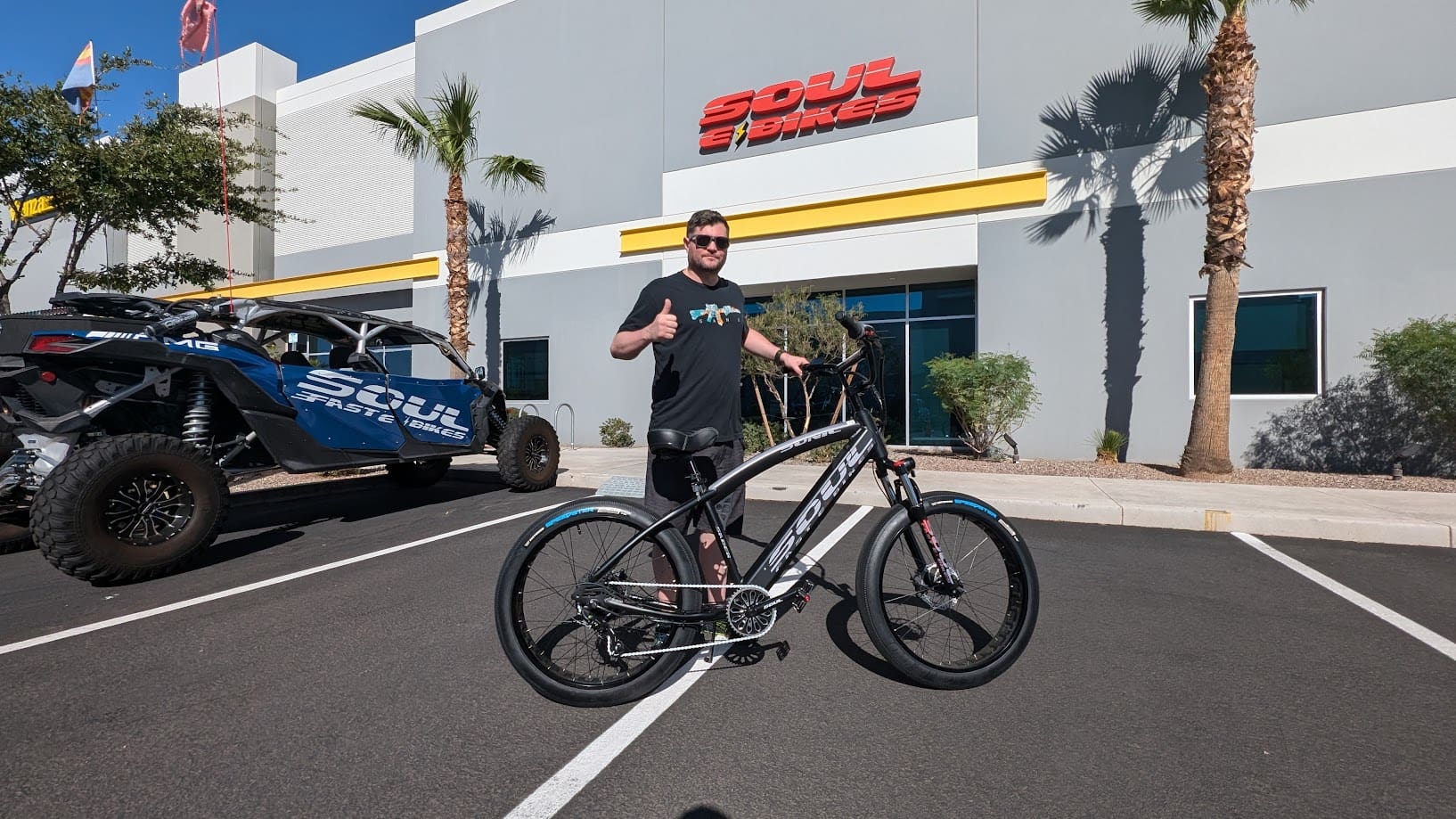 Man with bicycle outside Soul E Bikes store.