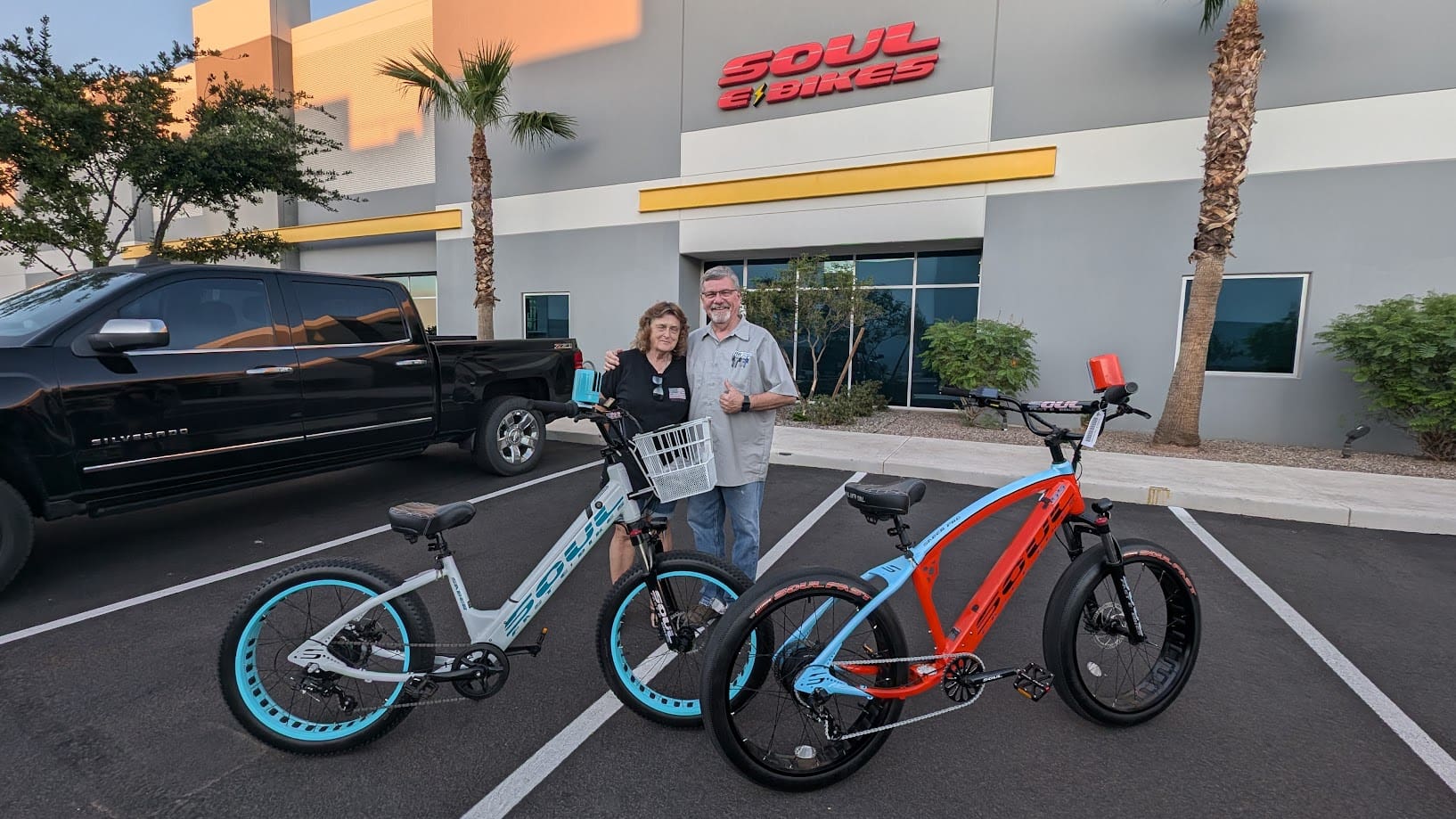 Two people standing with electric bicycles.