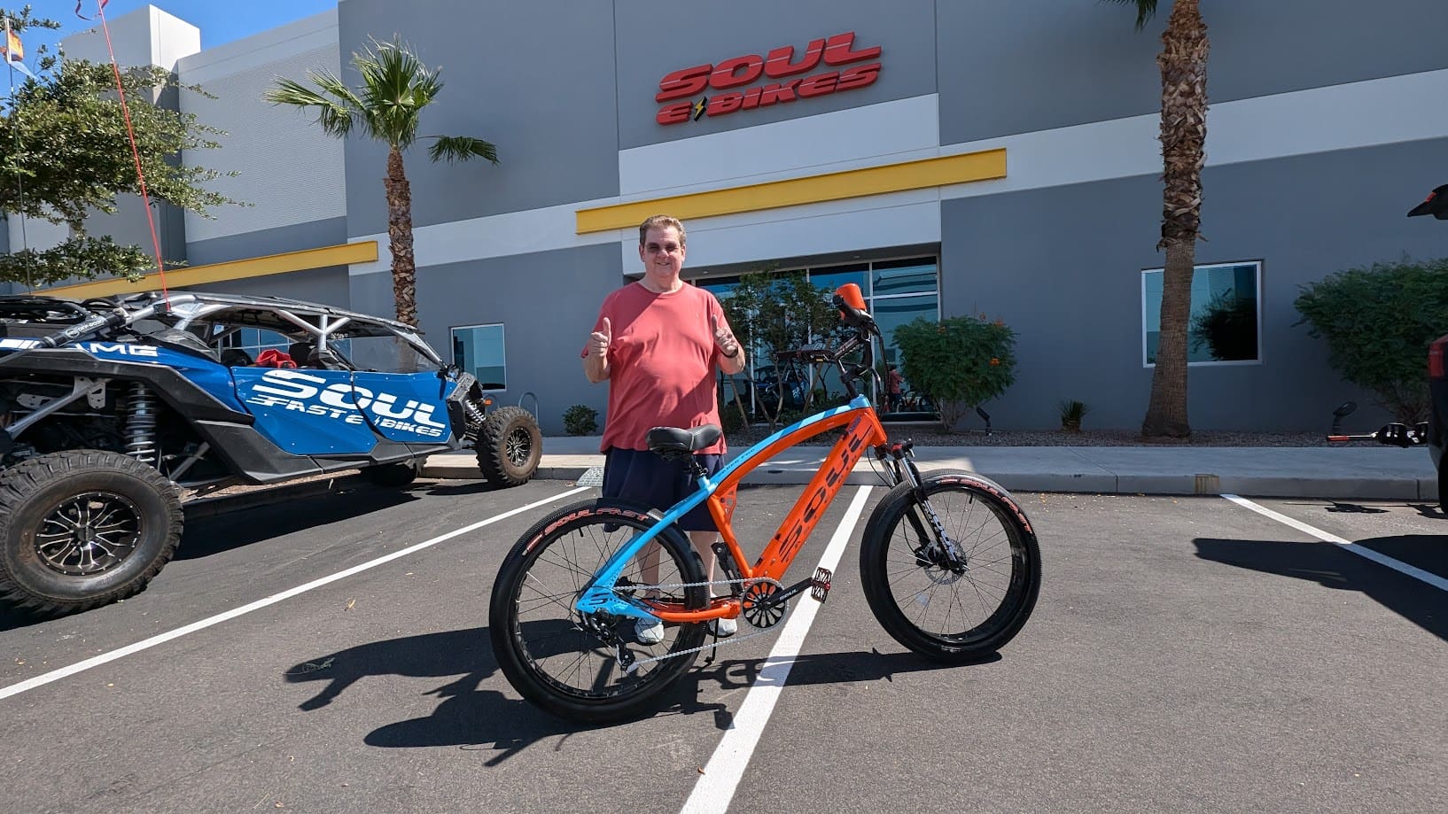Man standing with bicycle outside store.