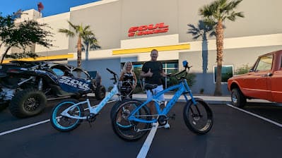 Two people with blue bicycles outside building.