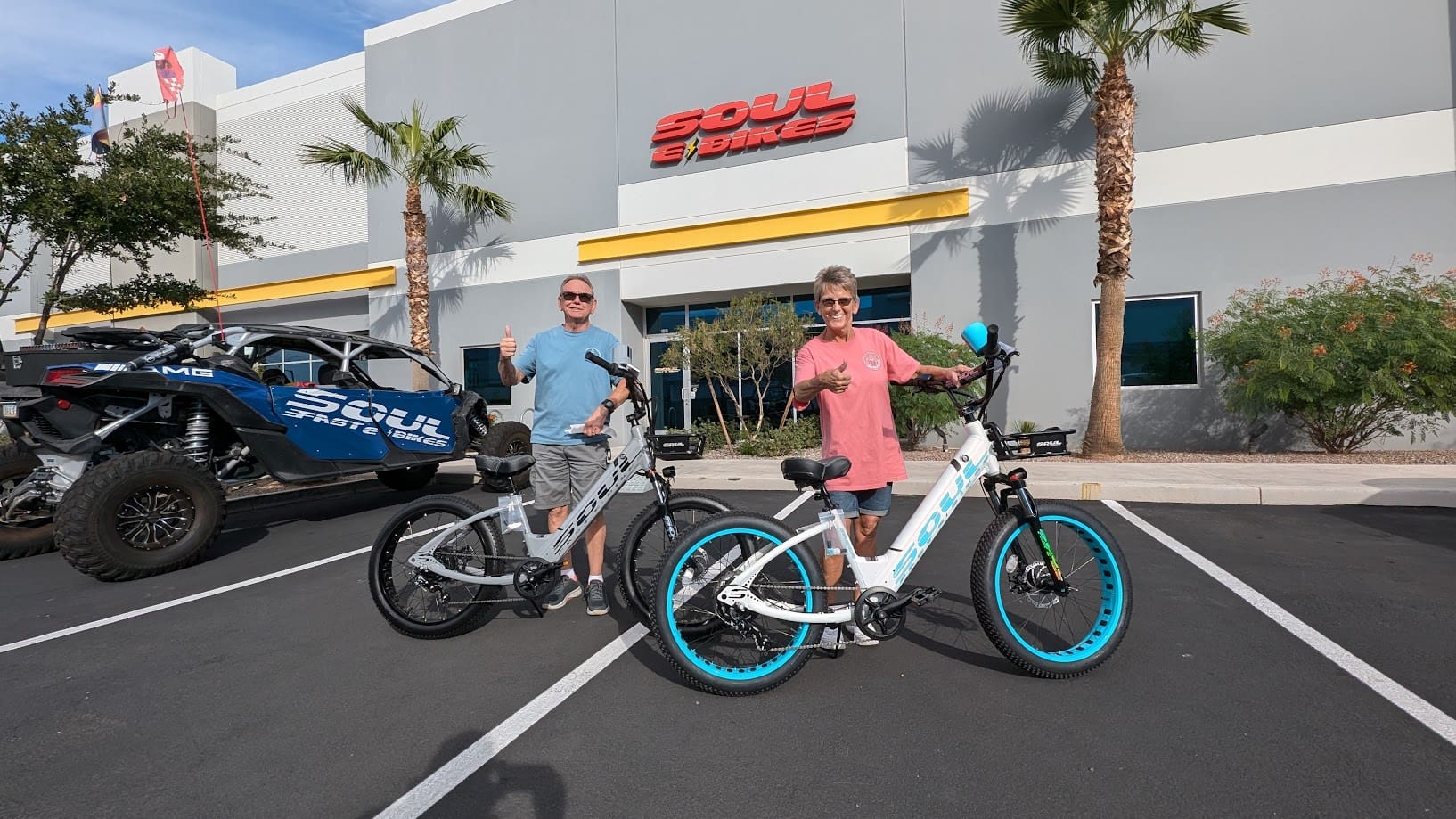 Two people with electric bikes outside store.