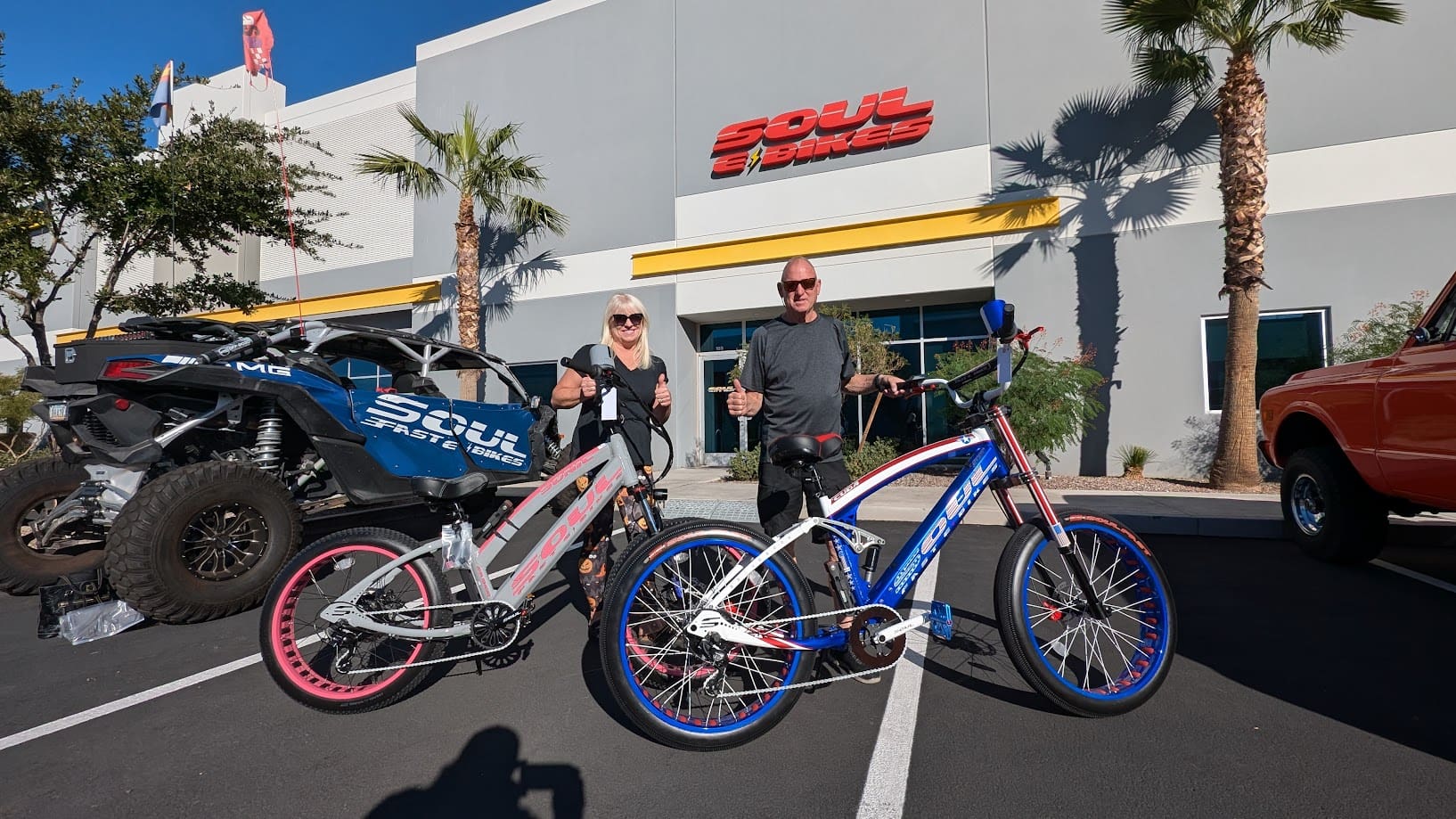 Two people with custom bicycles outside store.