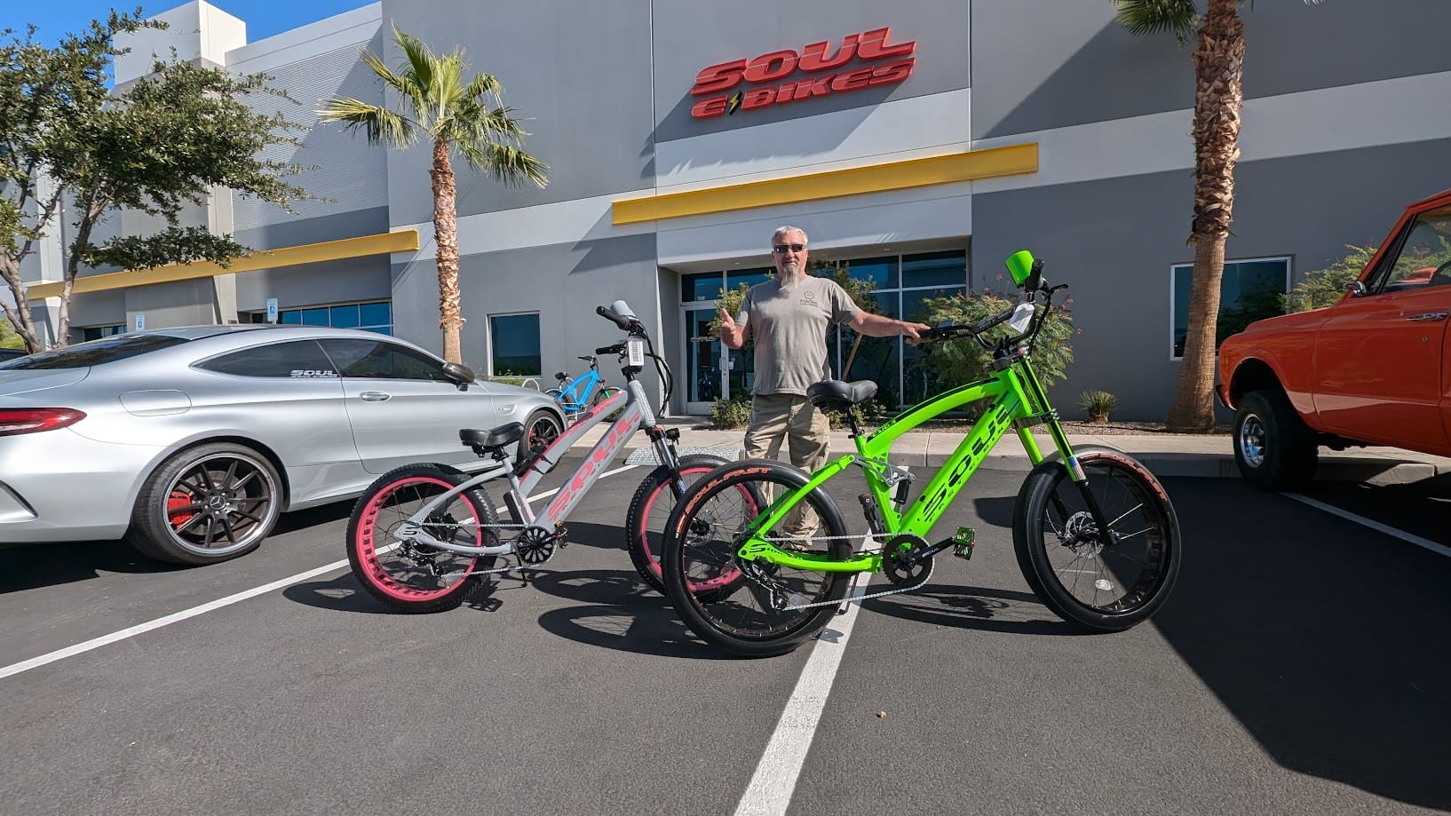 Man standing with two parked bicycles outside.
