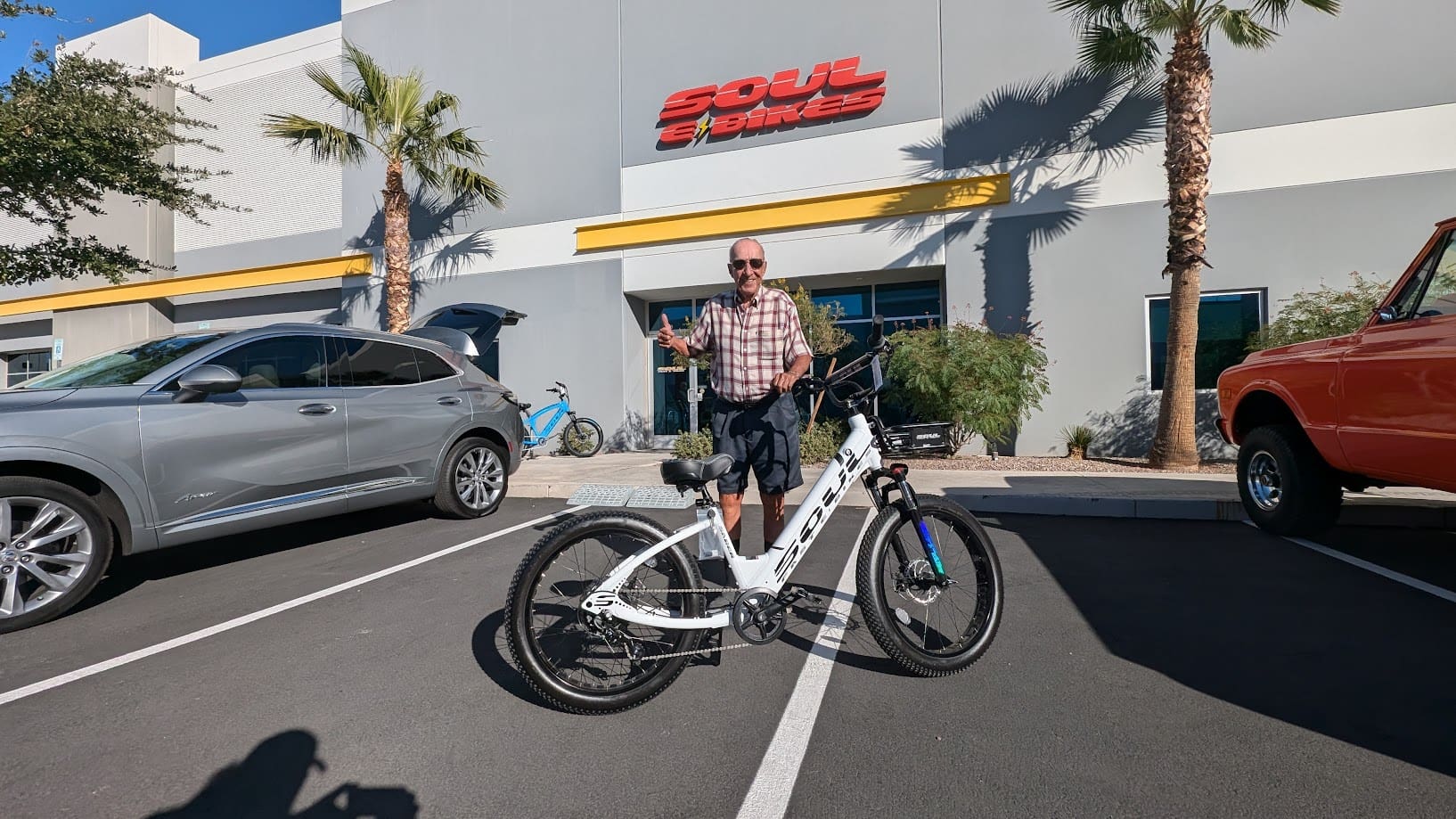 Man standing with white bicycle outside building.