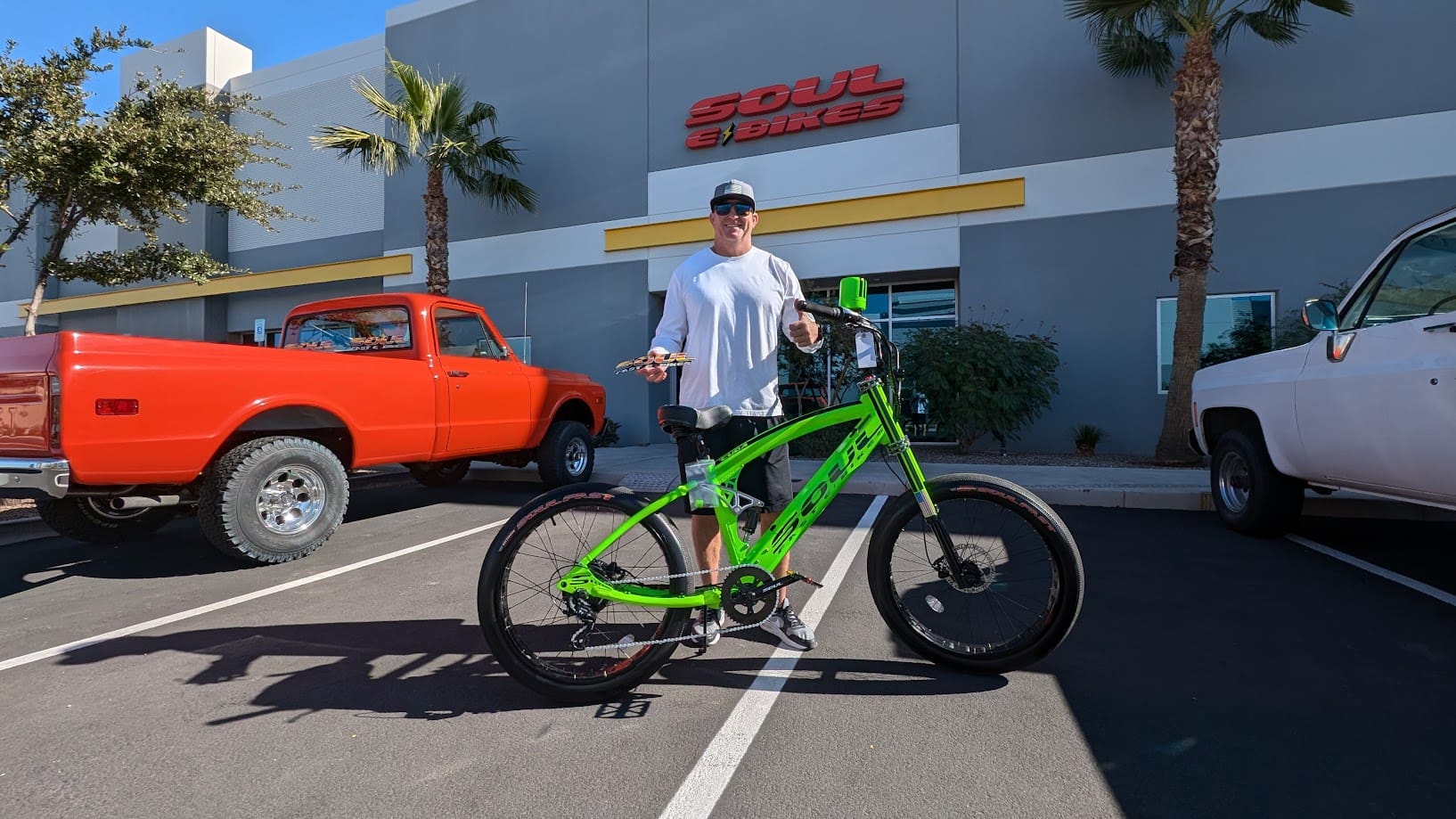 Man standing with green bicycle in parking lot.