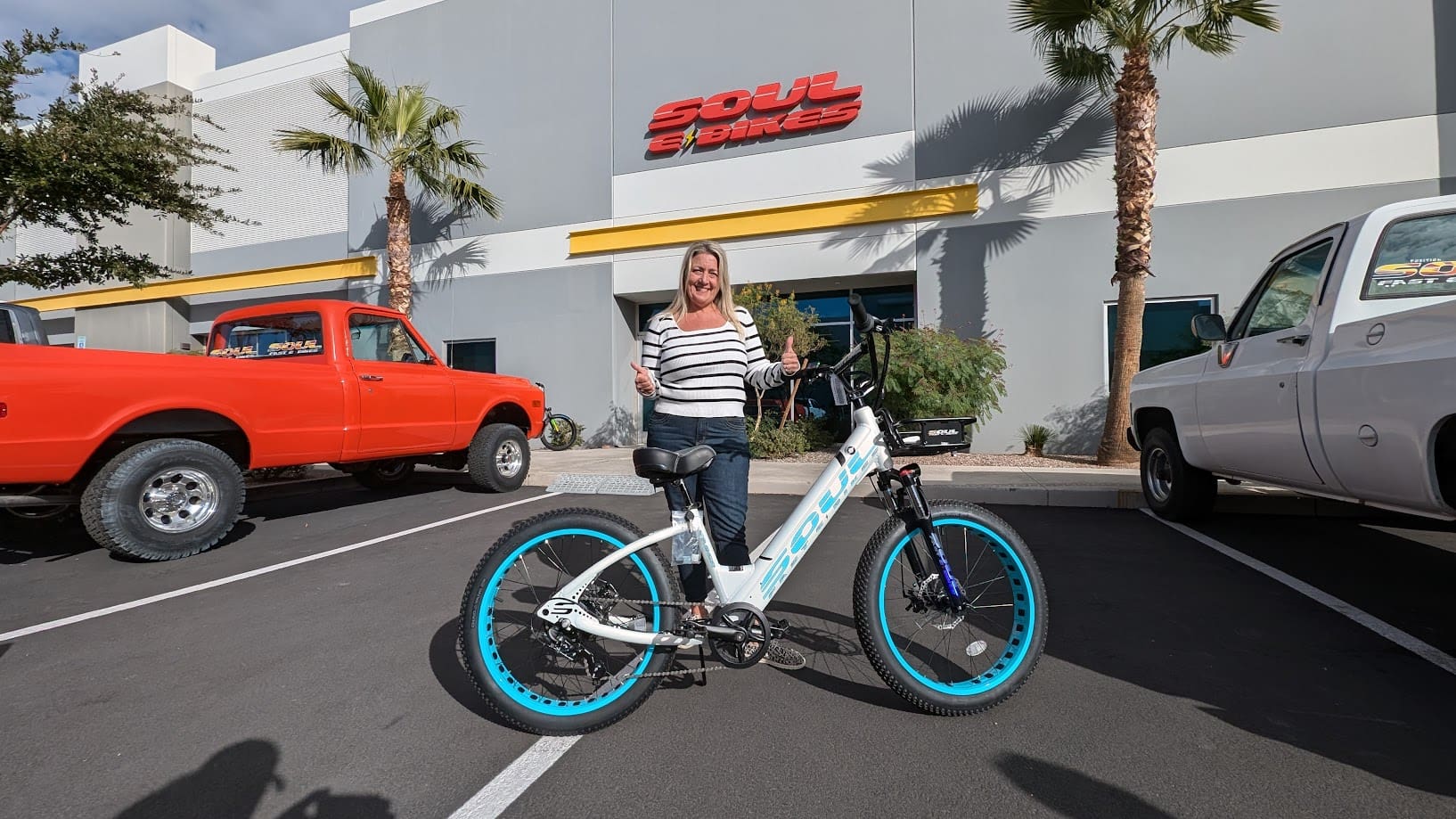 Woman smiling with bicycle in parking lot.