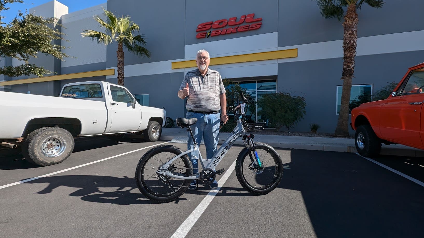 Man standing with a bicycle outside store.