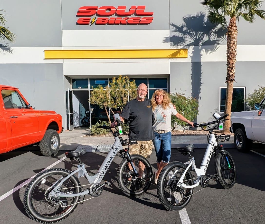 Couple with bicycles outside Soul E Bikes shop.
