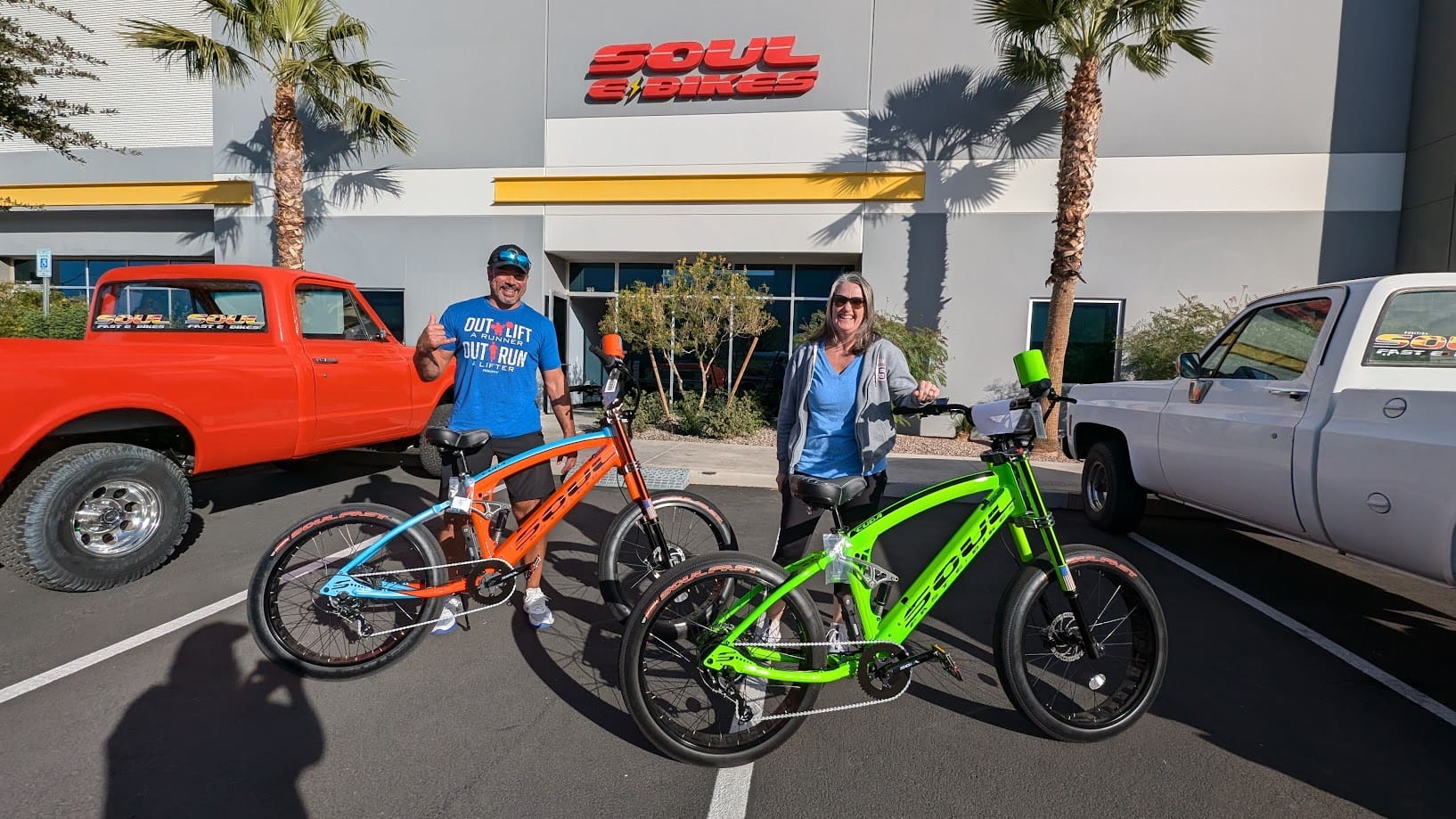 Two people with colorful electric bikes outside.