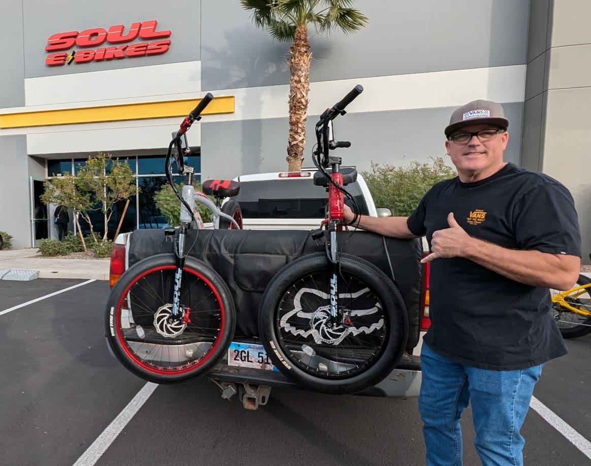 Man with bikes on truck outside store.
