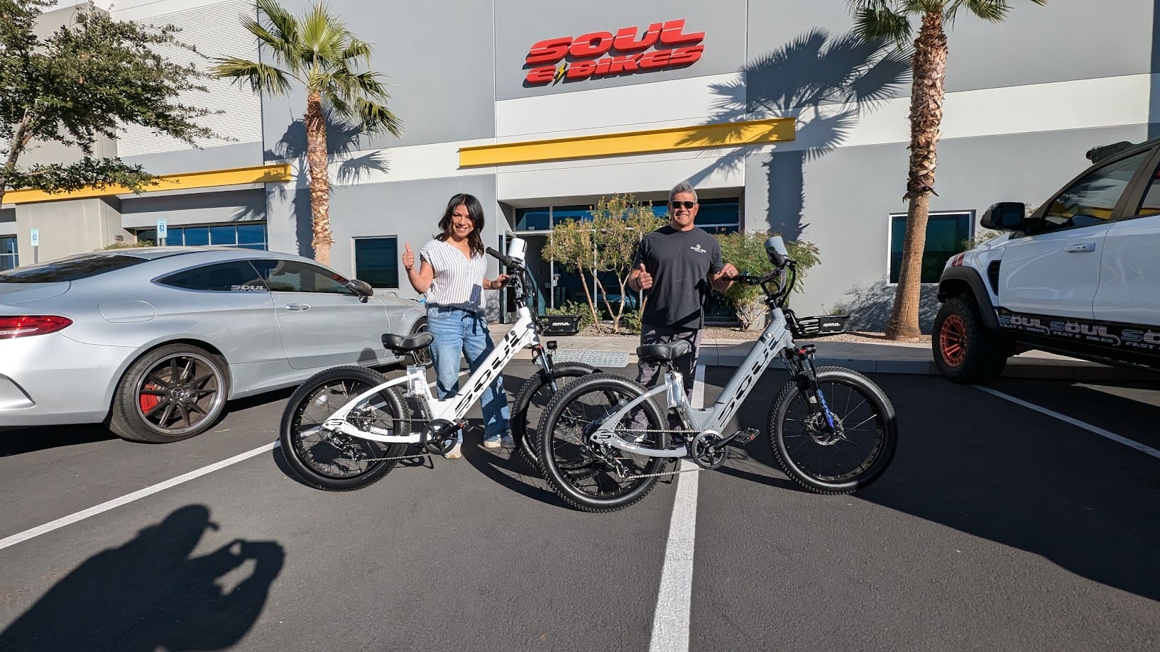 People with electric bikes outside store.