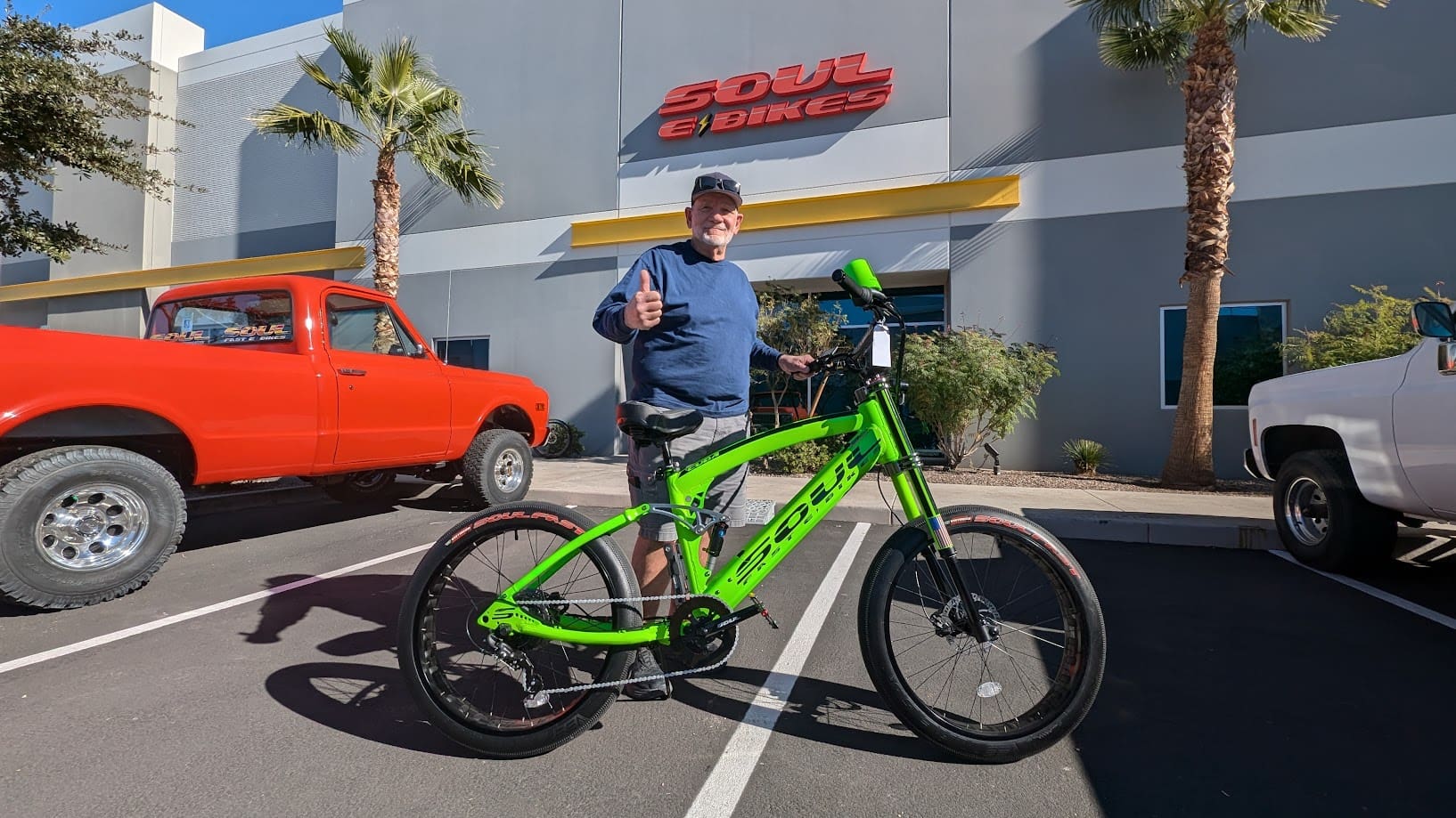 Man with green bicycle outside bike shop.