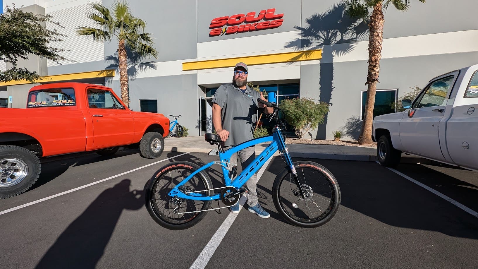 Man standing with blue bicycle outside building.