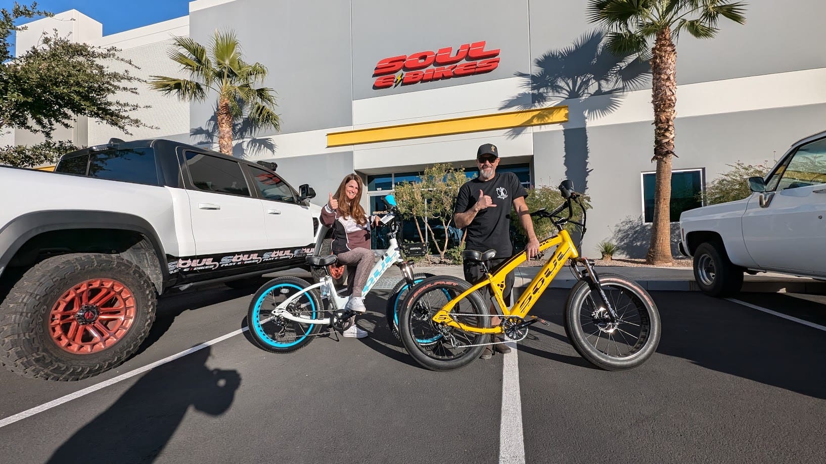 Two people posing with colorful bicycles.