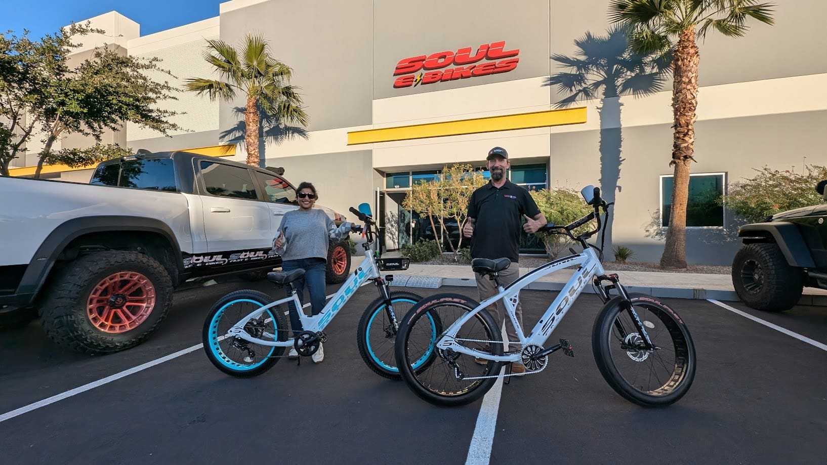 Two people with bicycles outside a building.