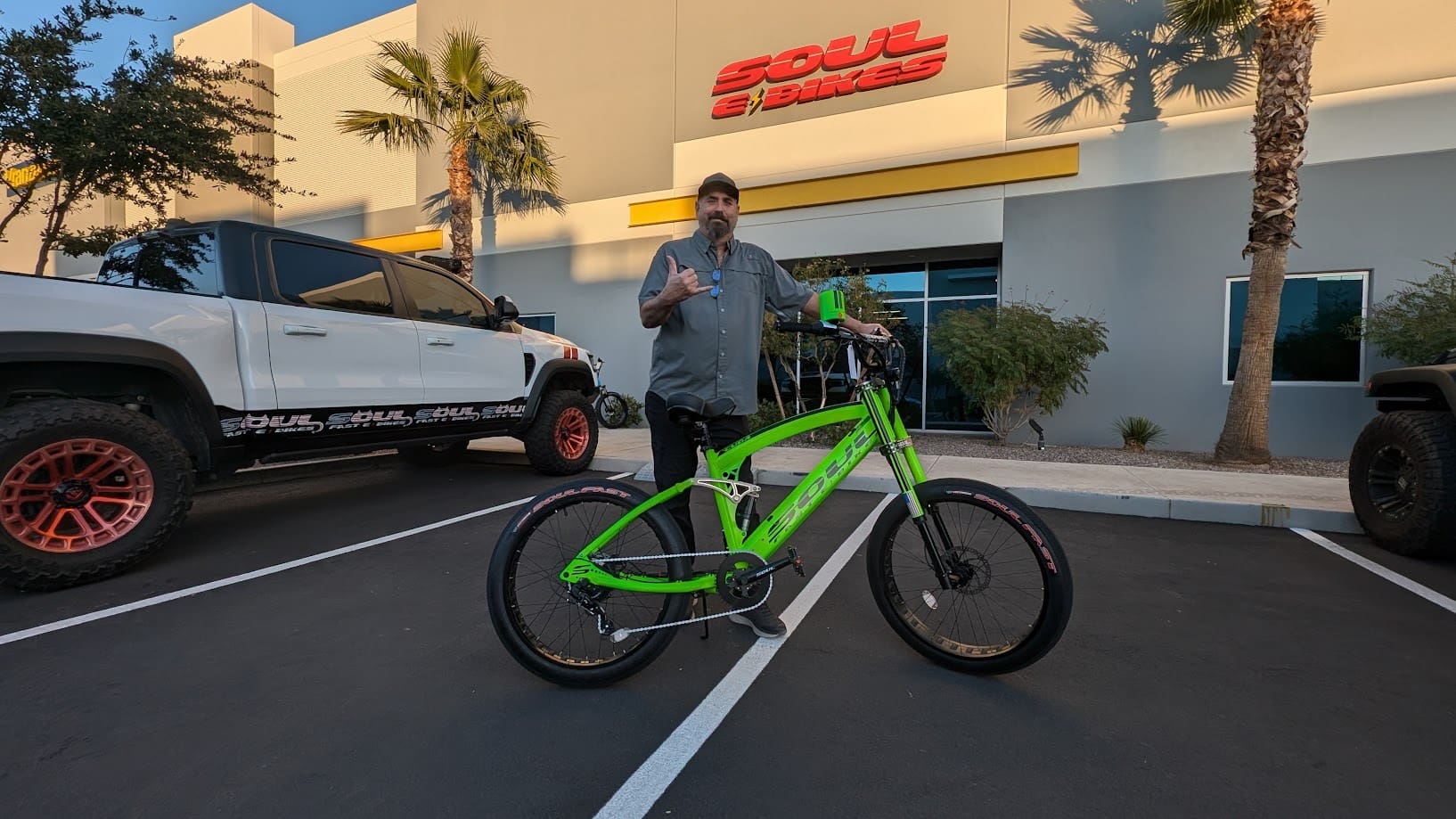 Man posing with green bicycle outside building.