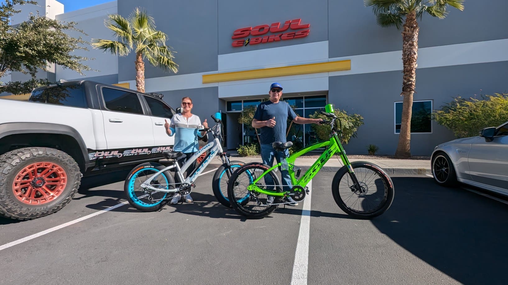 People posing with bikes outside a store.