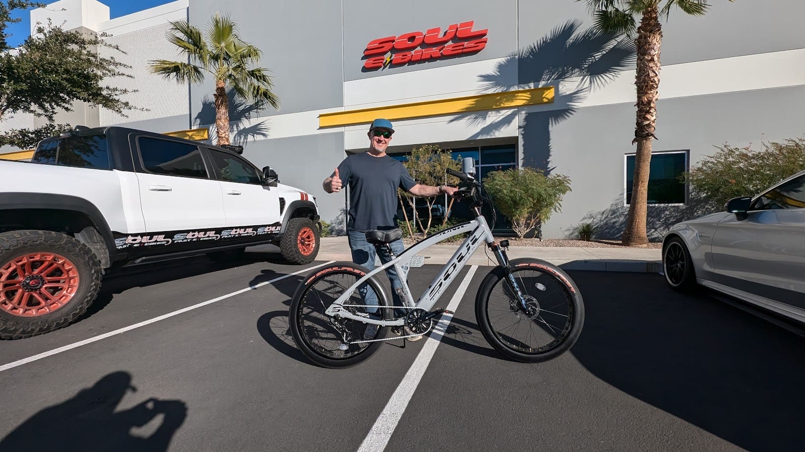 Man with bicycle outside building and truck.