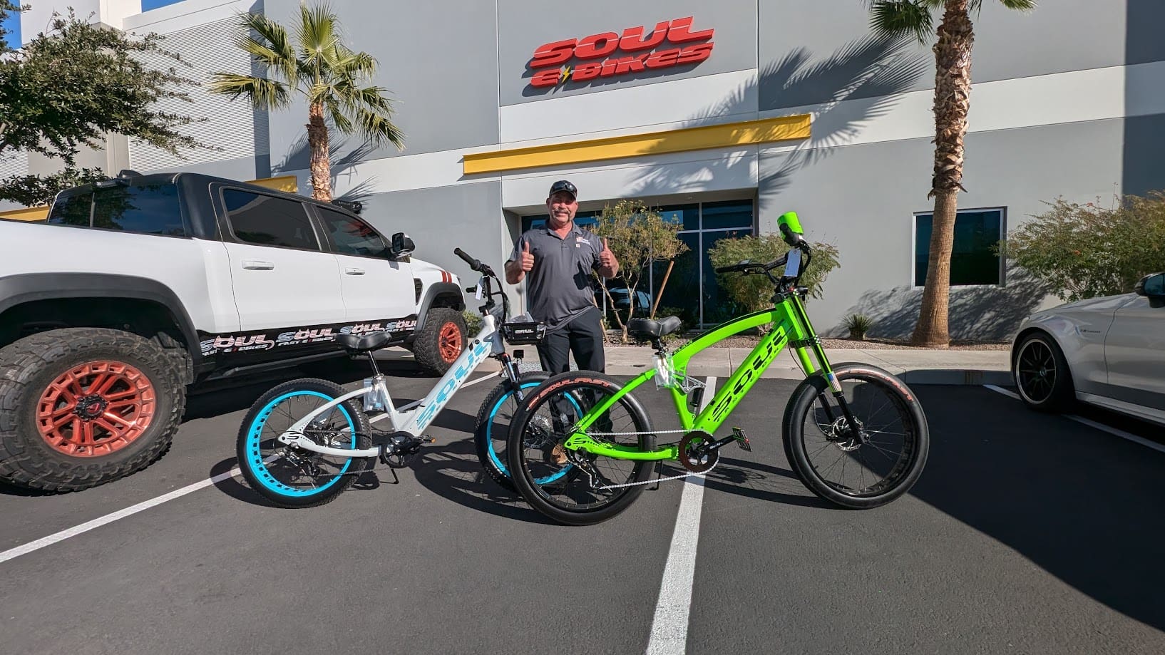 Man with two colorful bikes outside building.