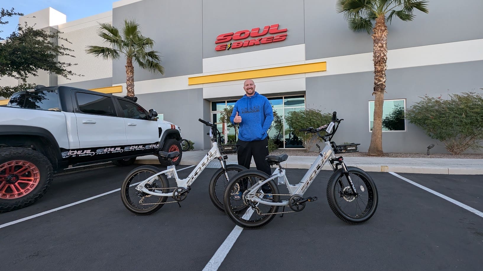 Man standing with two bicycles outside building.