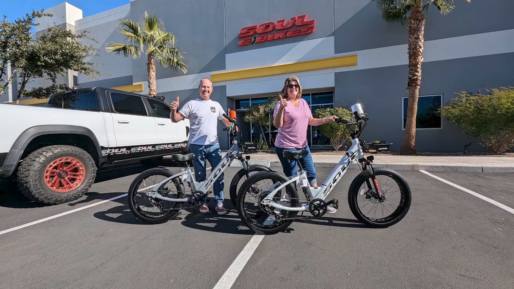 Two people with e-bikes outside store.