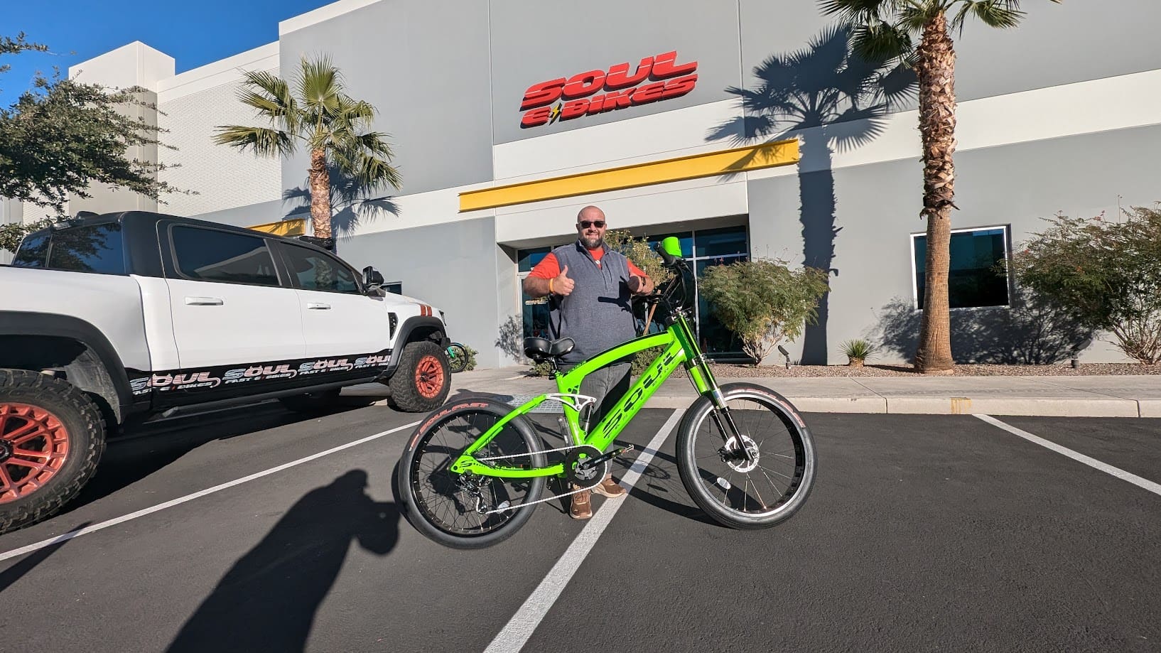 Man with green bicycle outside Soul Bikes store.