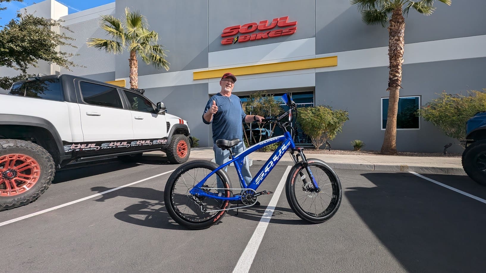 Man standing with blue bicycle in parking lot.