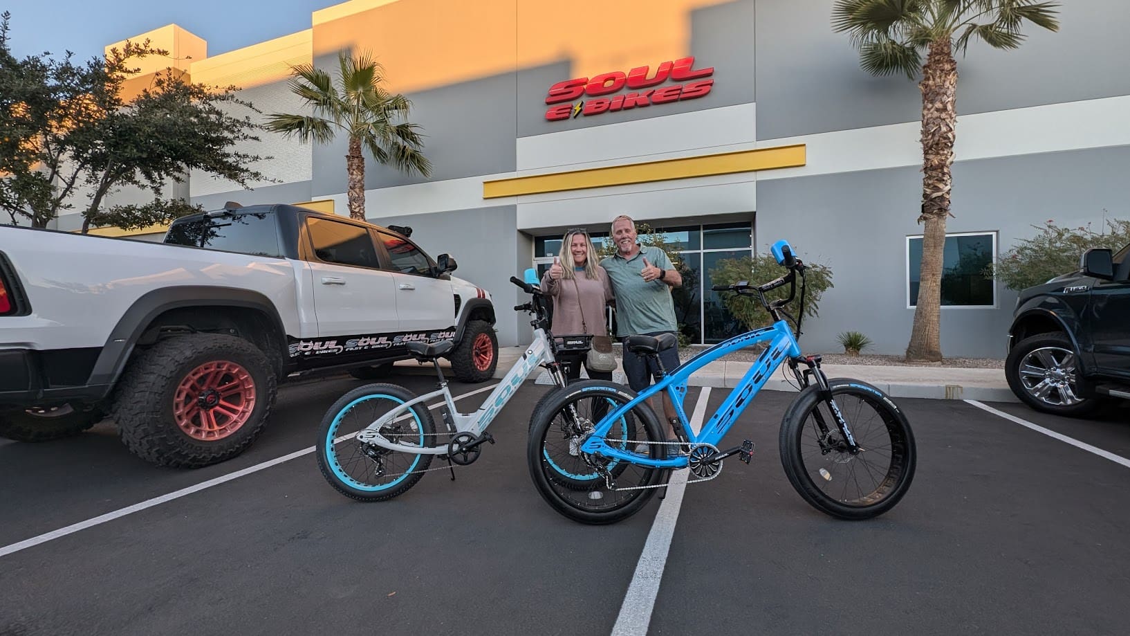 People posing with bikes outside a store.