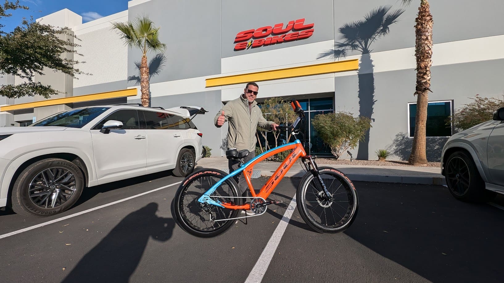 Man posing with colorful bike outside building.
