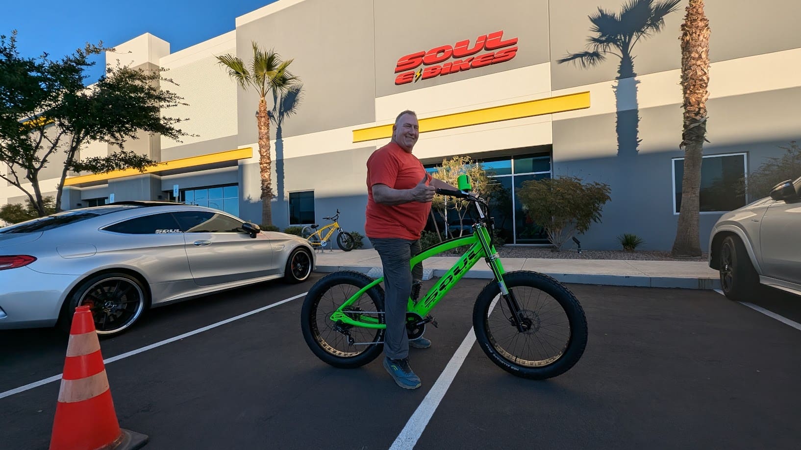 Man with green bike outside building.