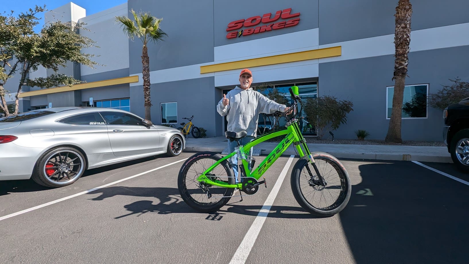 Person posing with green bicycle outside building.