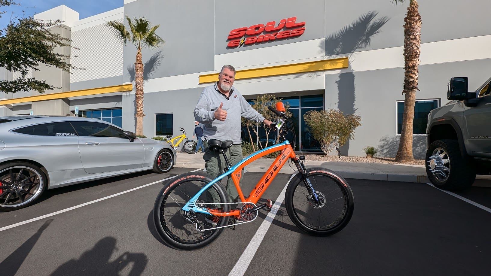 Man standing with bicycle outside building, smiling.