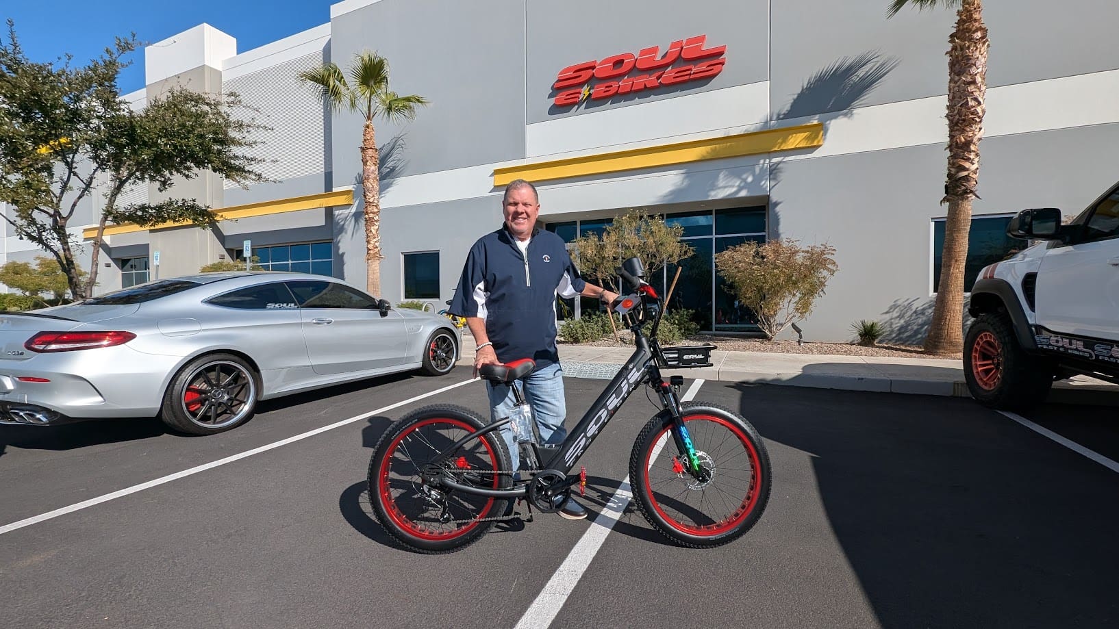 Man standing with bicycle in parking lot.