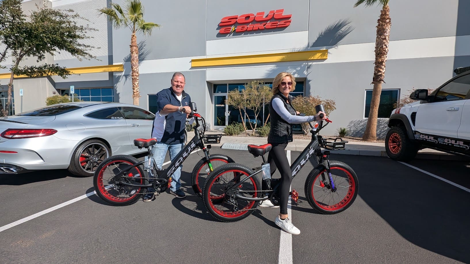 Two people with electric bikes outside store.