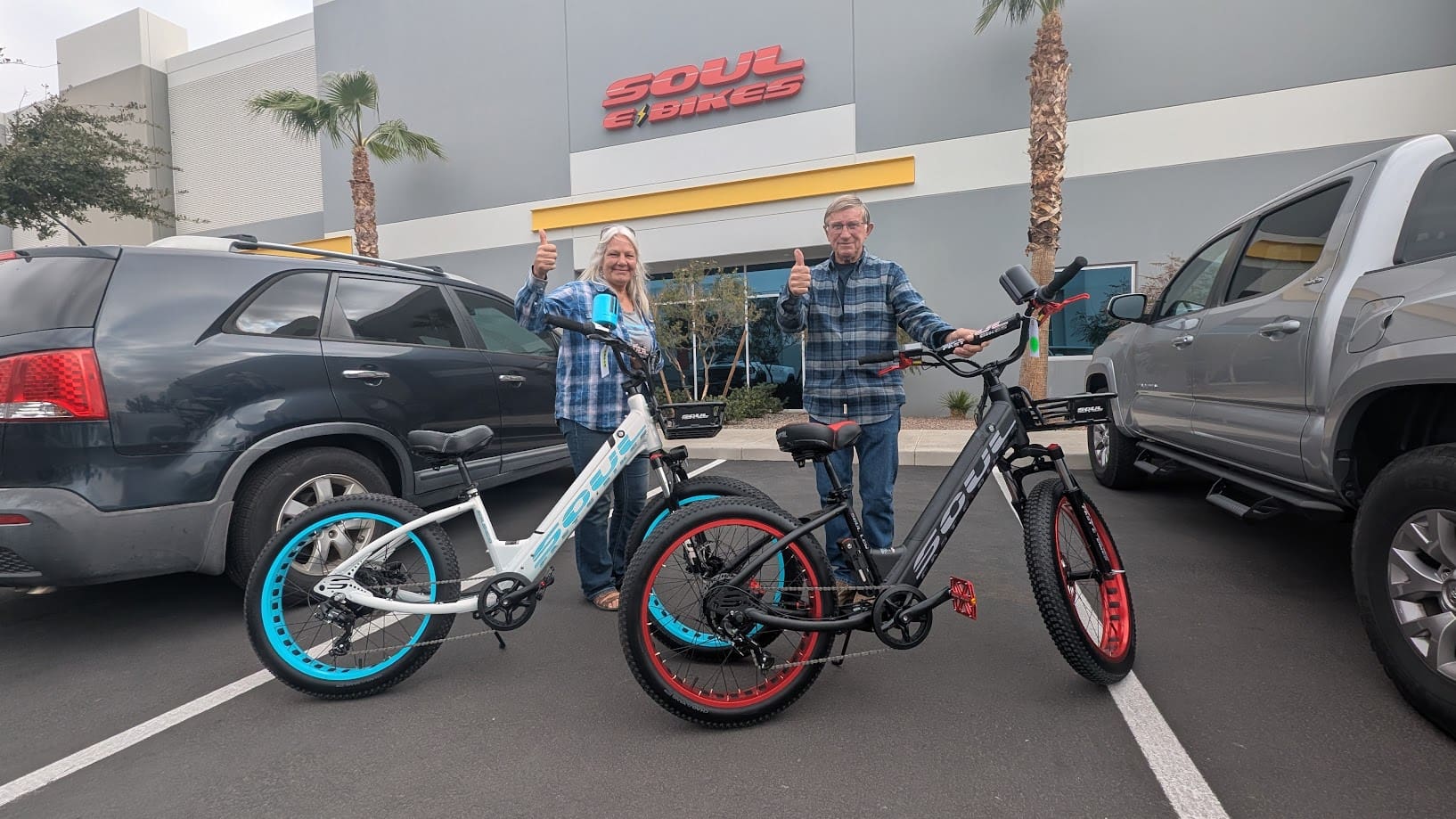 Two people with bicycles in parking lot.
