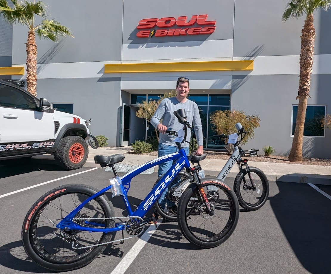 Man with two bikes outside bike shop.