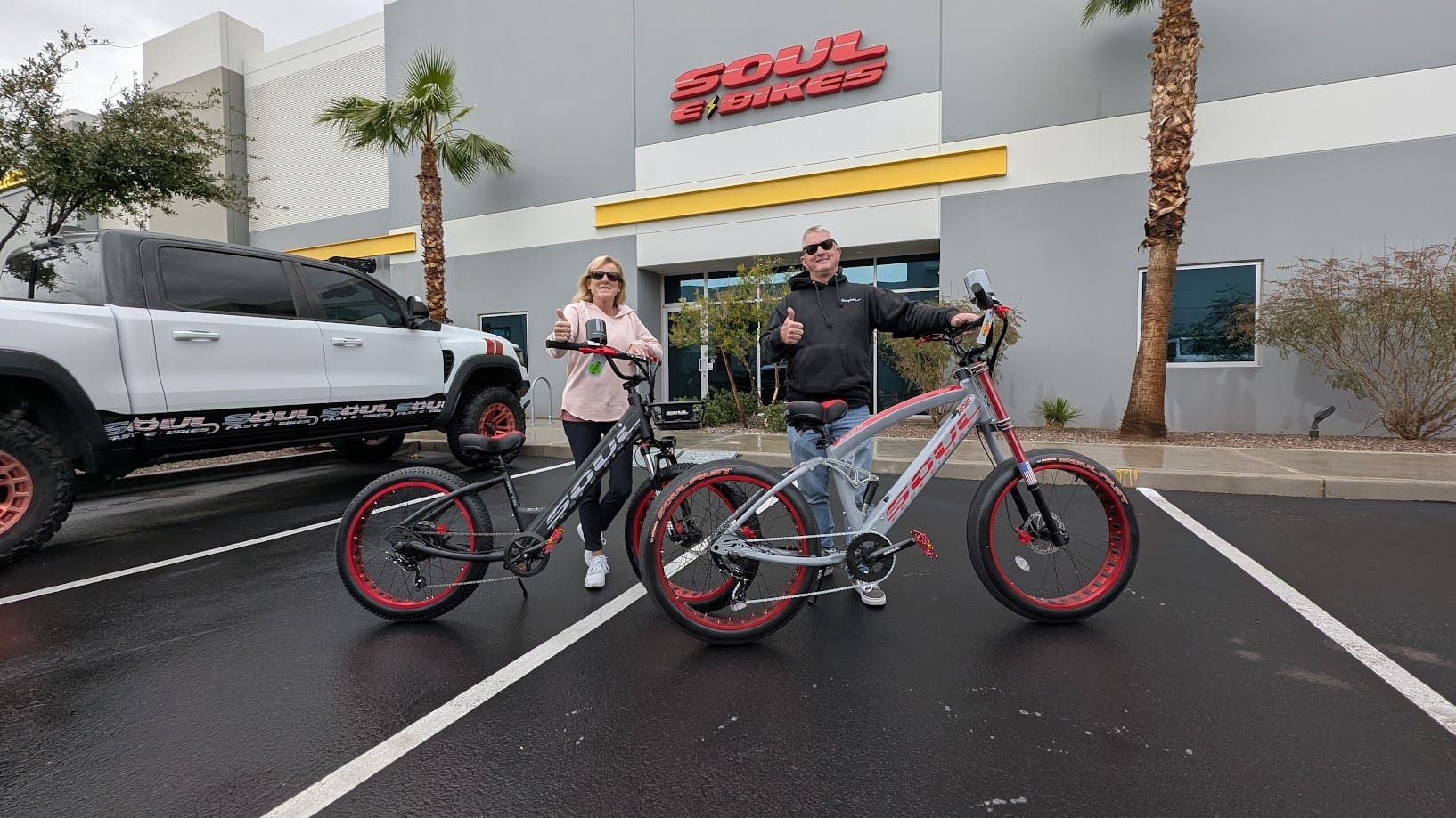 Two people with bikes outside bike store.