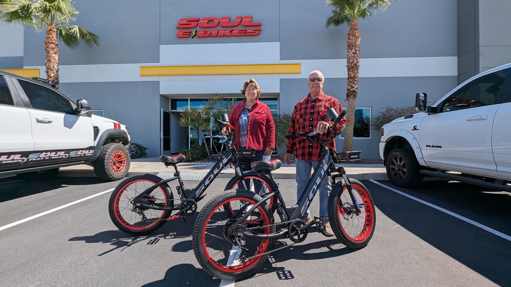 Two people with electric bikes outside store.