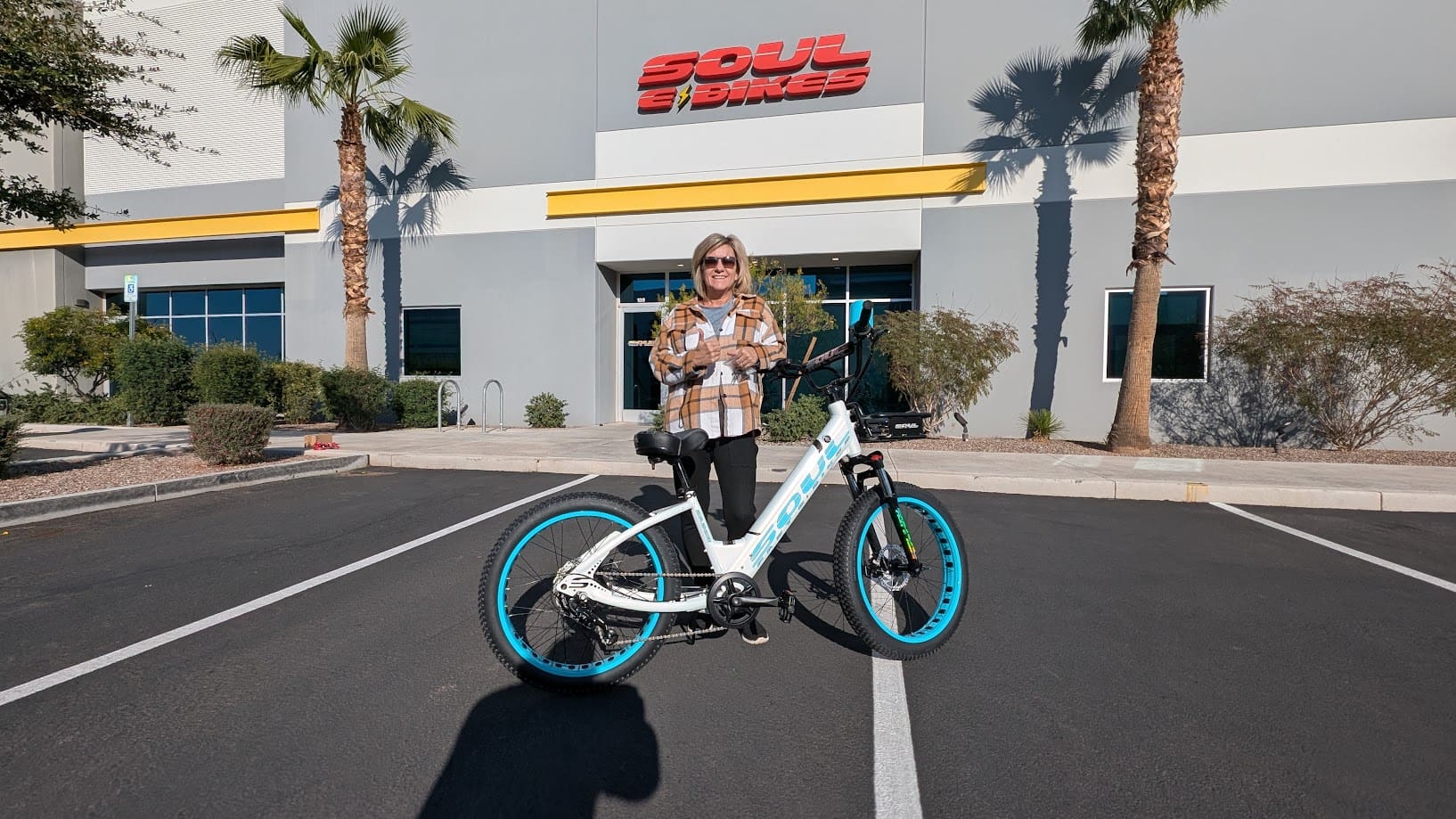 Person standing with bicycle in parking lot.