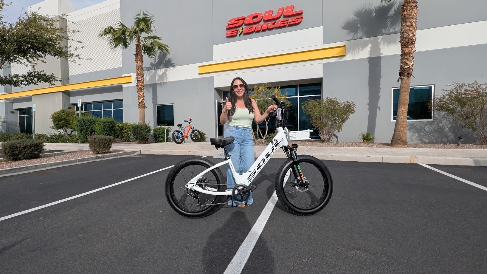 Woman standing with an electric bike outside.