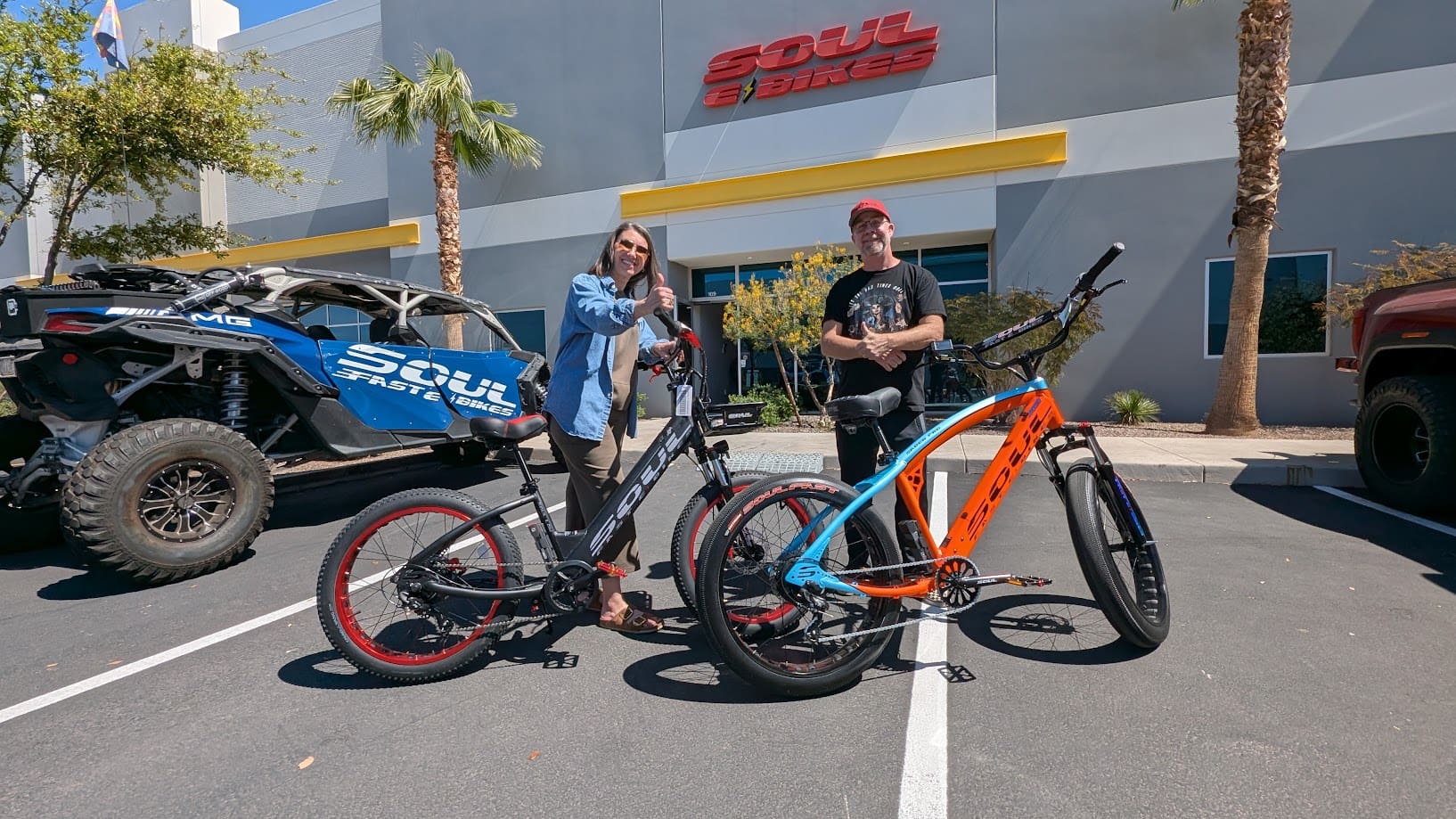 Two people with electric bikes outside store.