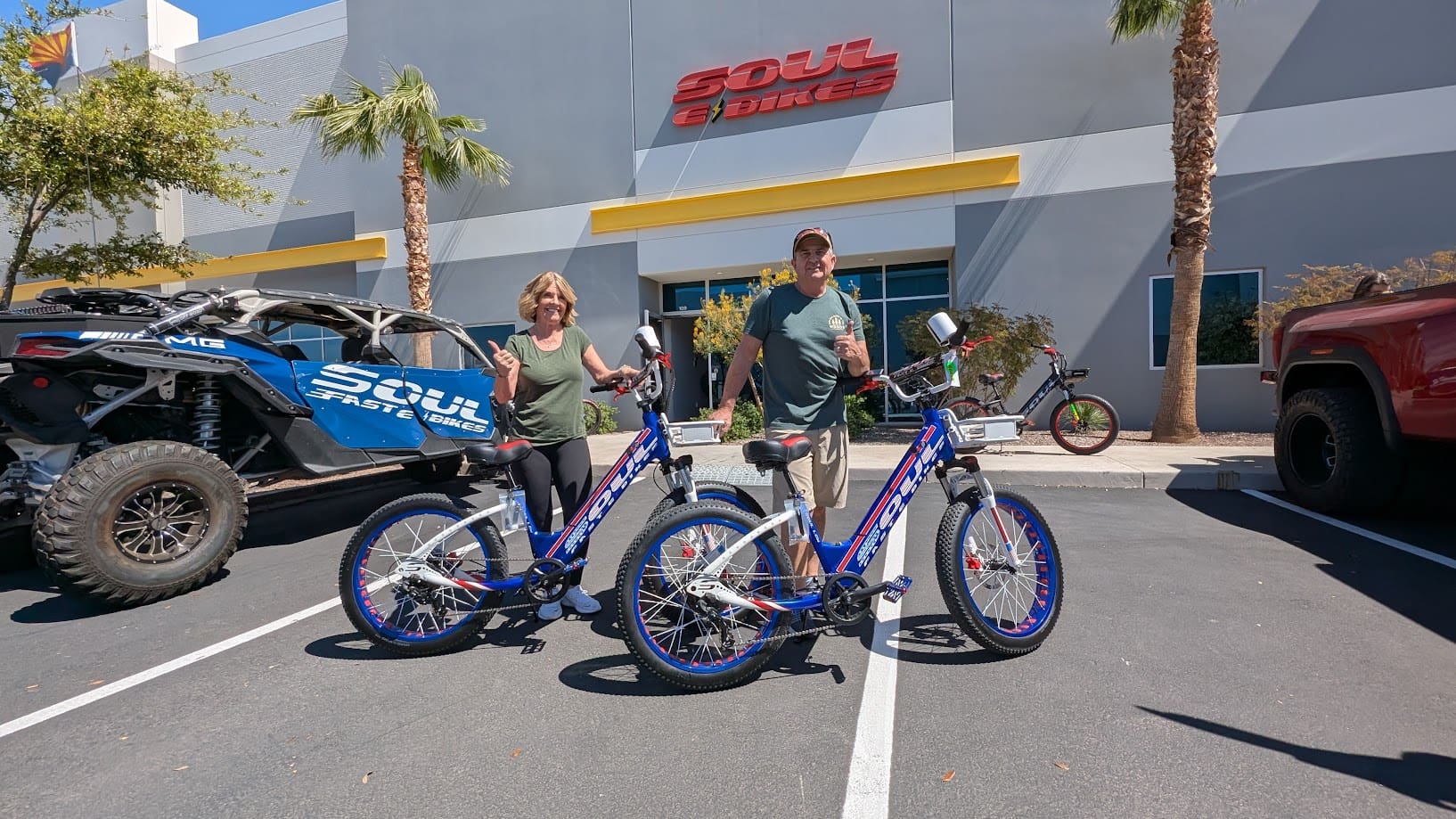 Two people with electric bikes outside store.