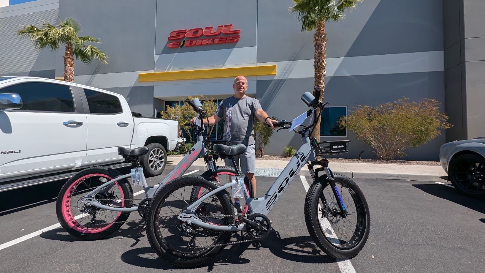 Man with two bikes outside a store.