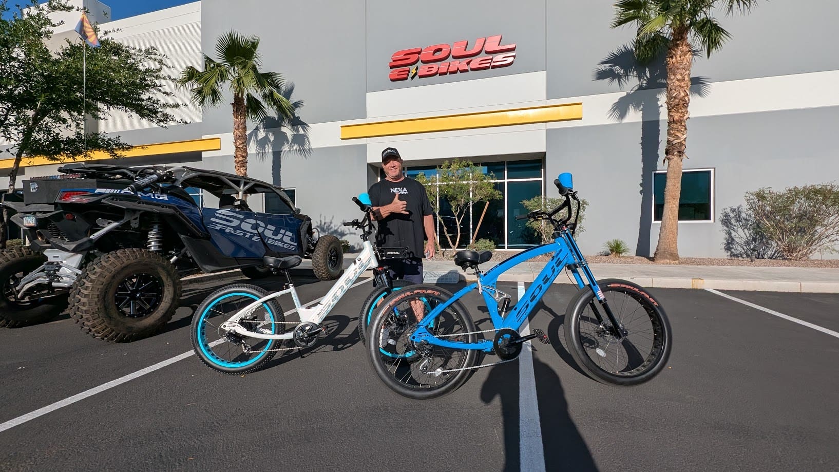 Man with two electric bikes outside store.